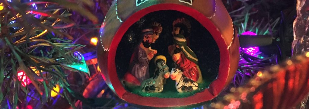 Christmas creche ornament on lit tree